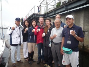 〈SAKURA〉の入港を祝し、ベイサイド・マリーナで乾杯。河野博文JSAF会長（左端）、永井環境委員長（左から3人目）、Matt（同４人目）、Nicole（同５人目）、神奈川県連の貝道和昭会長(右から２人目)